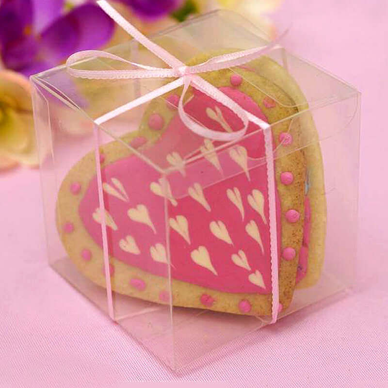 Heart-shaped cookie in clear box with pink icing and decorative hearts.