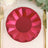 Red geometric paper plate on a table setting with gold cutlery.