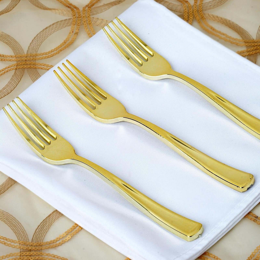 Set of three elegant gold forks on a white napkin.