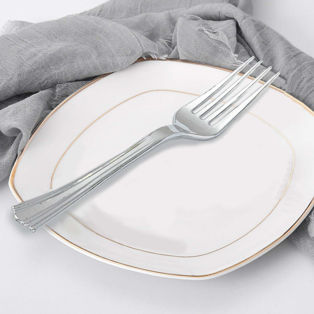 Silver fork on an elegant plate with a gray linen napkin.