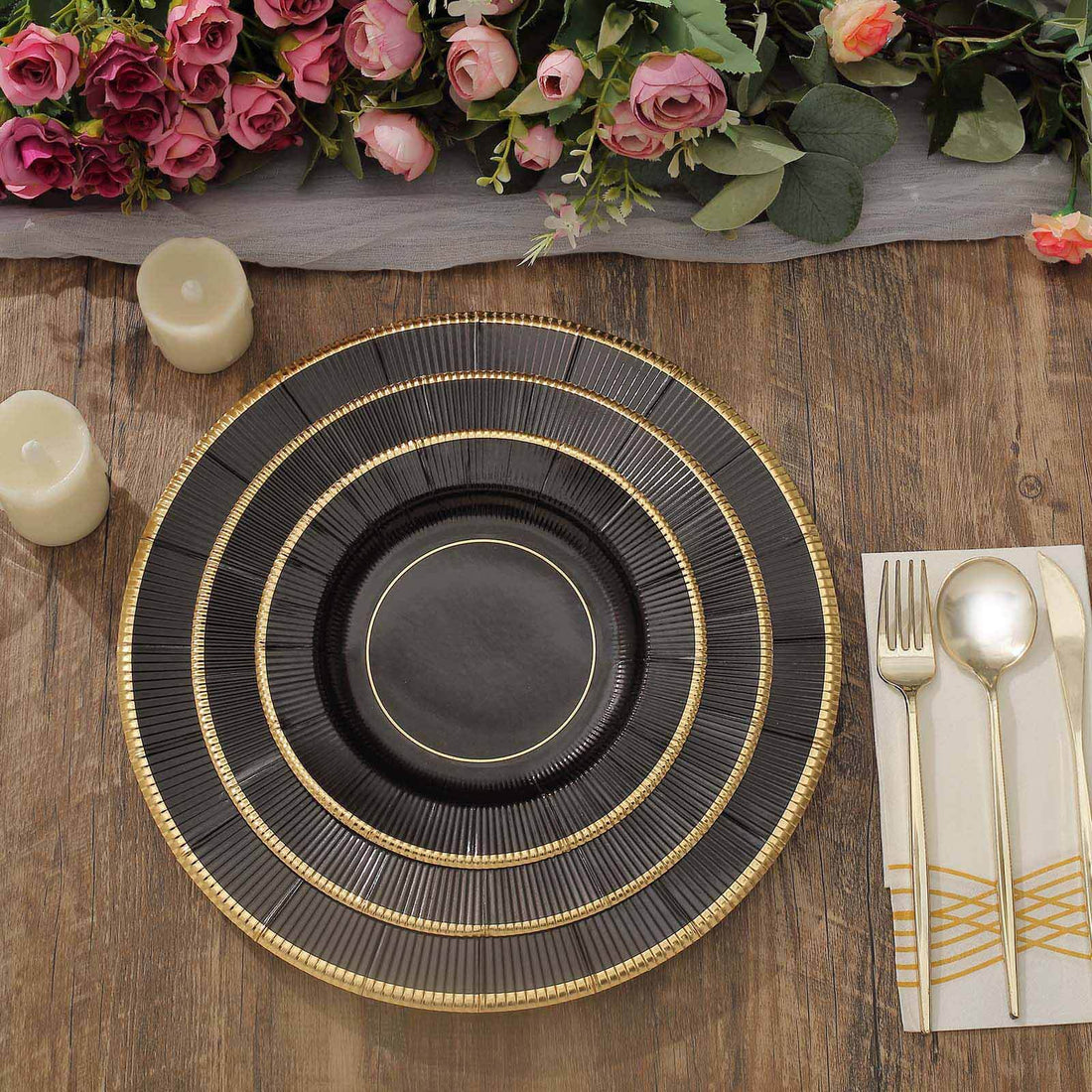 Elegant black and gold dinner plate set on rustic wooden table with floral arrangement.