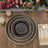 Elegant black and gold dinner plate set on rustic wooden table with floral arrangement.