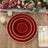 Elegant red and gold dinner plates set on a rustic wooden table with candles and flowers.