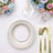 Elegant silver charger plate with gold utensils and floral arrangement.