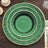 Green decorative plate with gold accents on a wooden table.