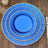 Blue decorative charger plate with gold accents on a wooden table.