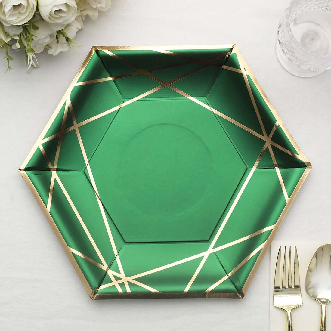Green hexagonal plate with gold geometric accents on a table setting.