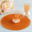 Orange tulle fabric with a tied pouch and floral arrangement on a wooden surface.