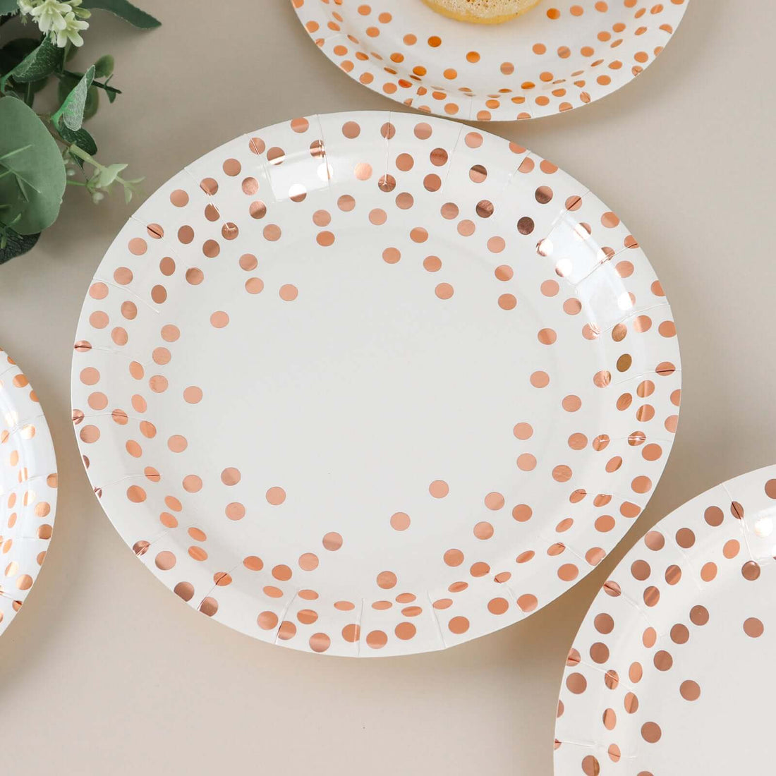 White paper plate with rose gold polka dots on a neutral background.