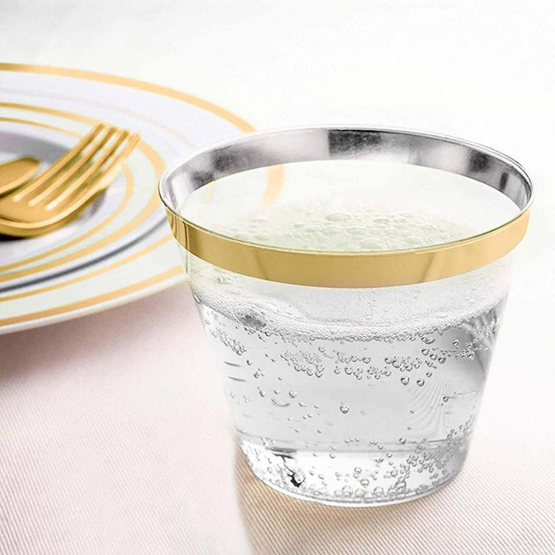 Clear glass tumbler with gold rim filled with sparkling water.