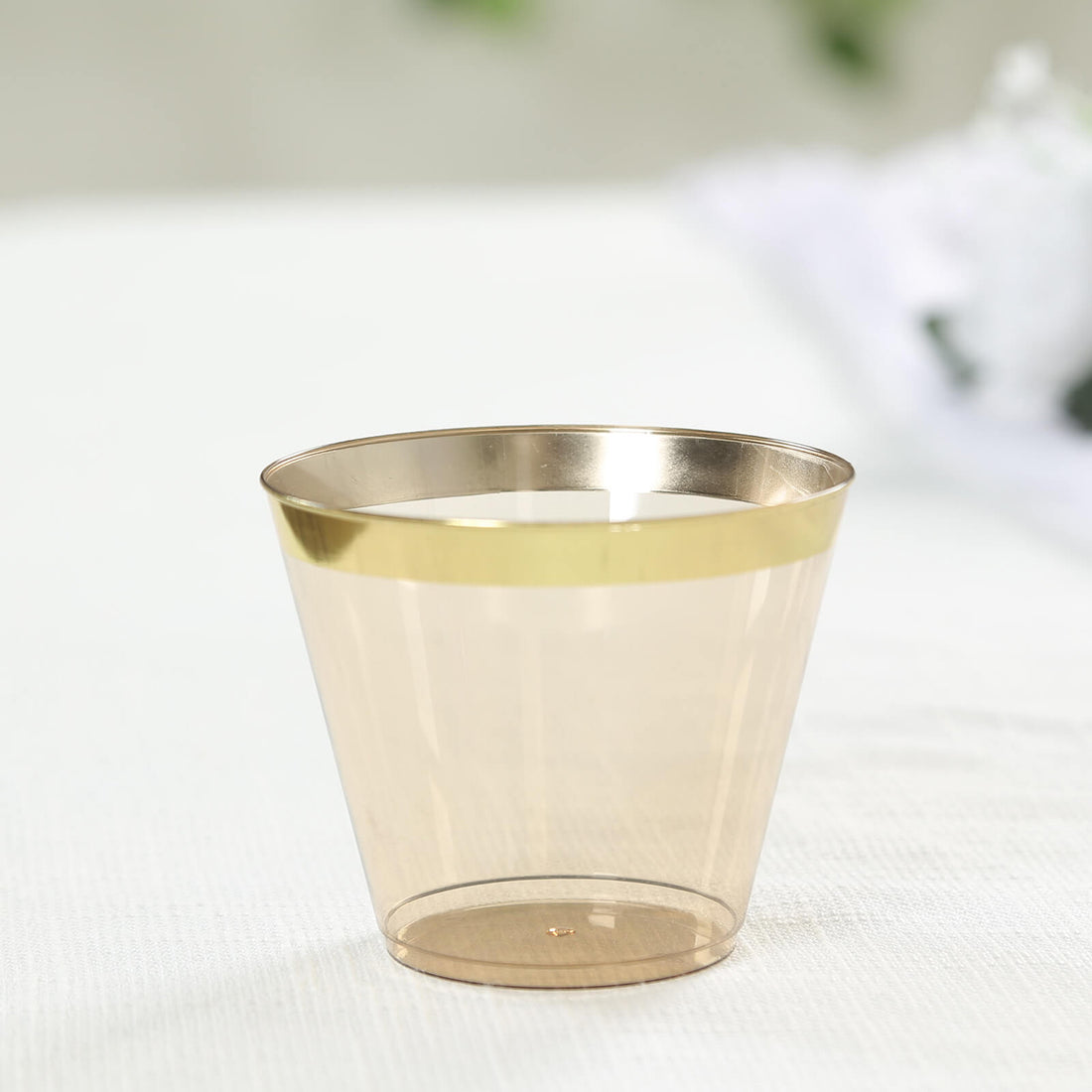 Clear plastic cup with a gold rim on a white surface.