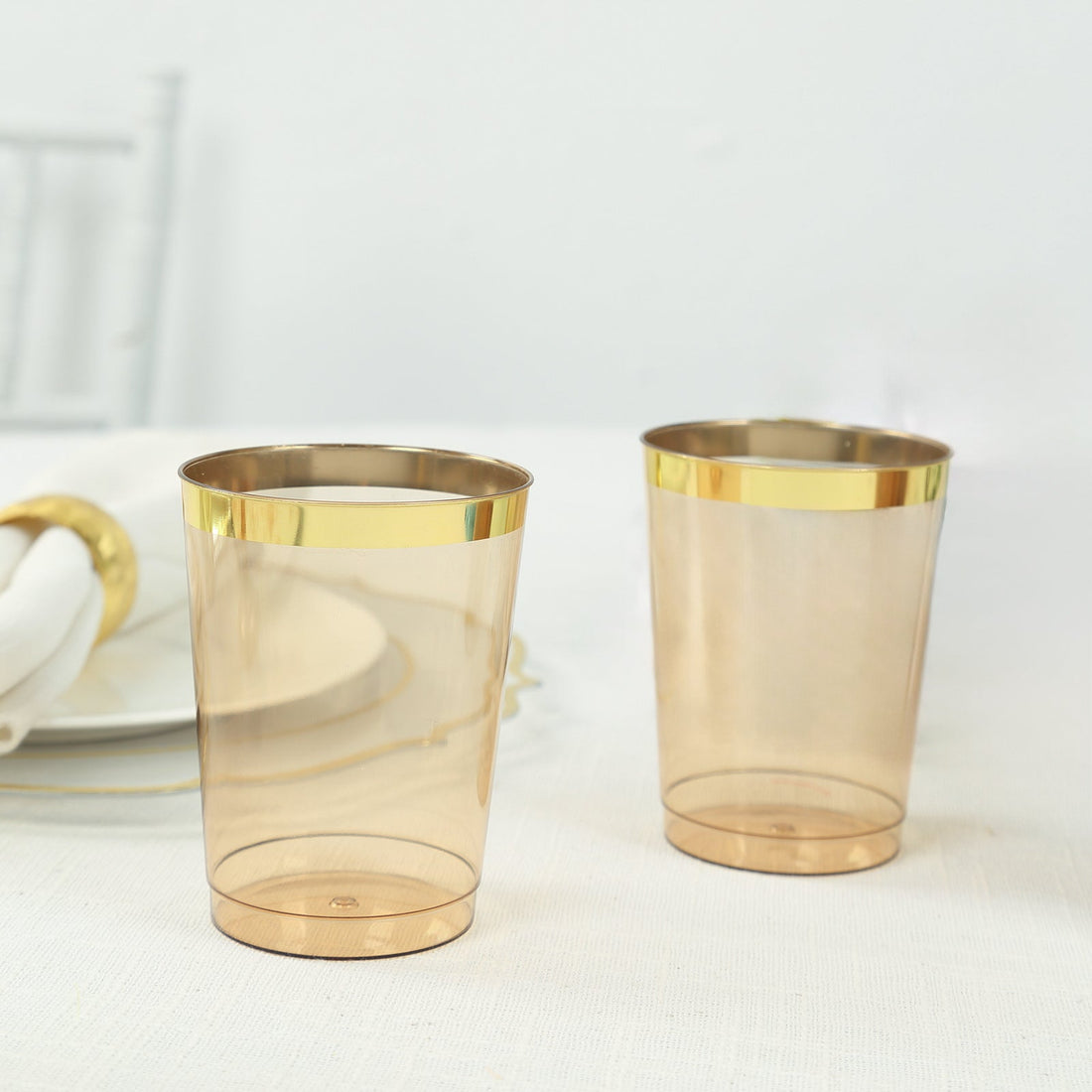 Two elegant transparent cups with gold rims on a light table setting.
