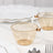 Transparent amber tea cup with gold trim, set on a light marble surface.