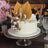 Elegant cake with decorative leaves and chocolate spheres on a glass stand.