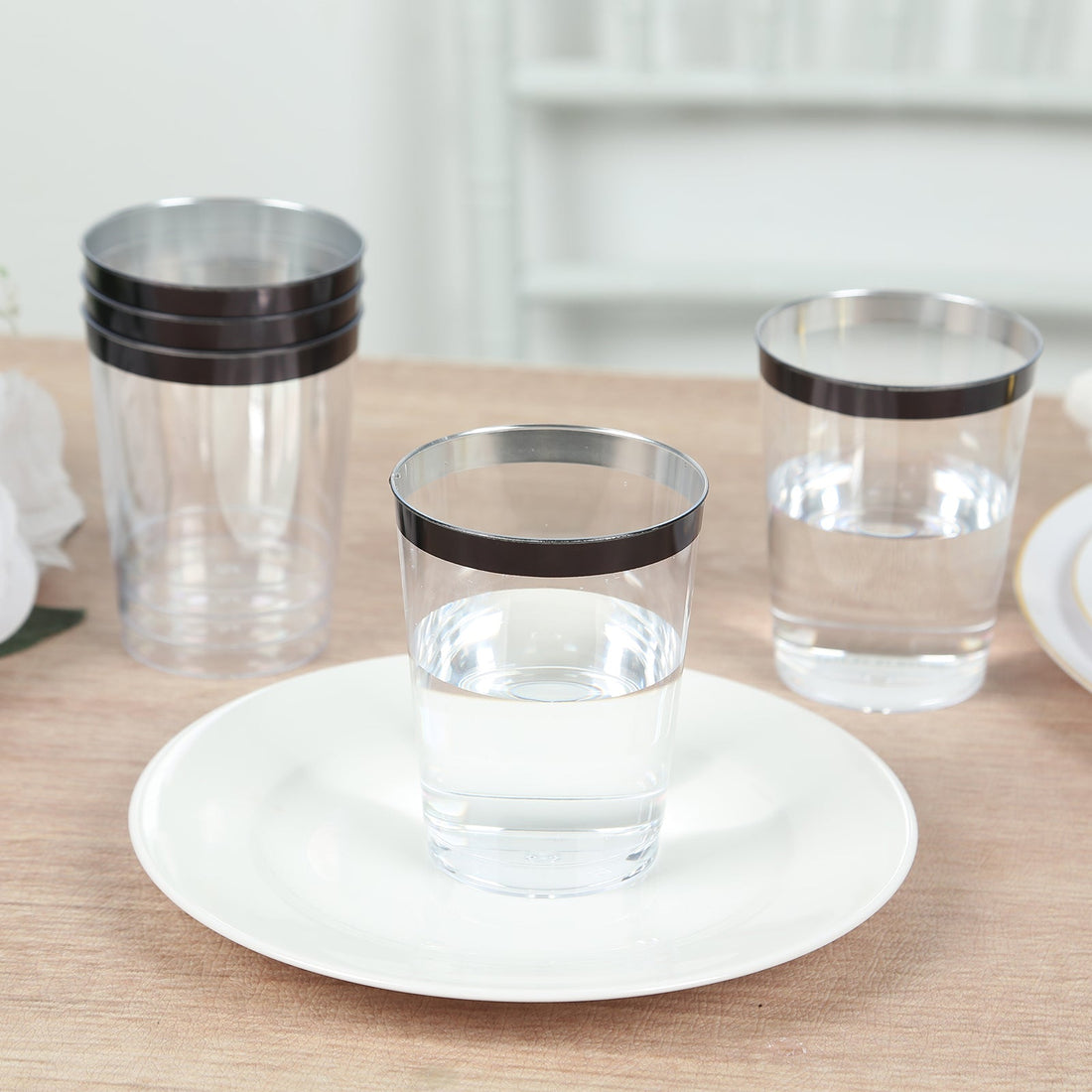 Clear drinking glasses with black rims on a white plate.
