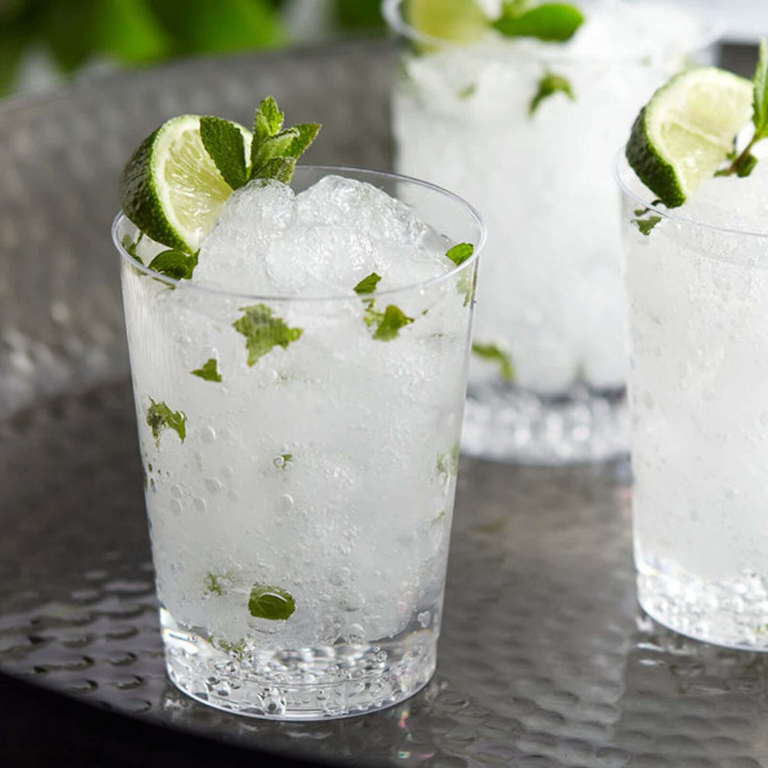 Refreshing mojito cocktails with mint and lime on a silver tray.