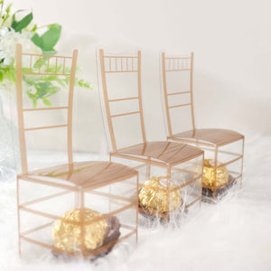 Three transparent chairs with gold accents and chocolates inside, styled on a soft, fluffy surface.