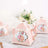 Pink floral tea party favor boxes with gold accents and ribbon.