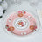 Pink floral plate with rose design and gold accents on a white background.