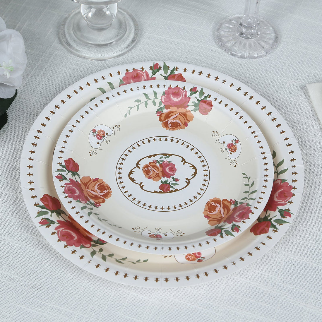 Floral-patterned dinner plates stacked on a textured tablecloth.