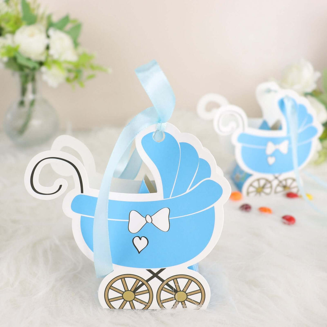 Blue baby carriage gift tags with ribbon accents on a soft background.