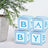 Blue baby blocks stacked next to a decorative plant.