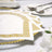Elegant white napkins with gold Greek key design on a dining table.
