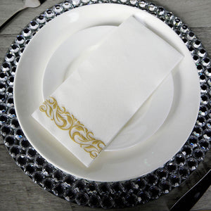 Elegant white napkin with gold design on a decorative plate.