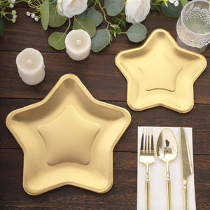 Gold star-shaped plates with gold utensils and candles on a wooden table.