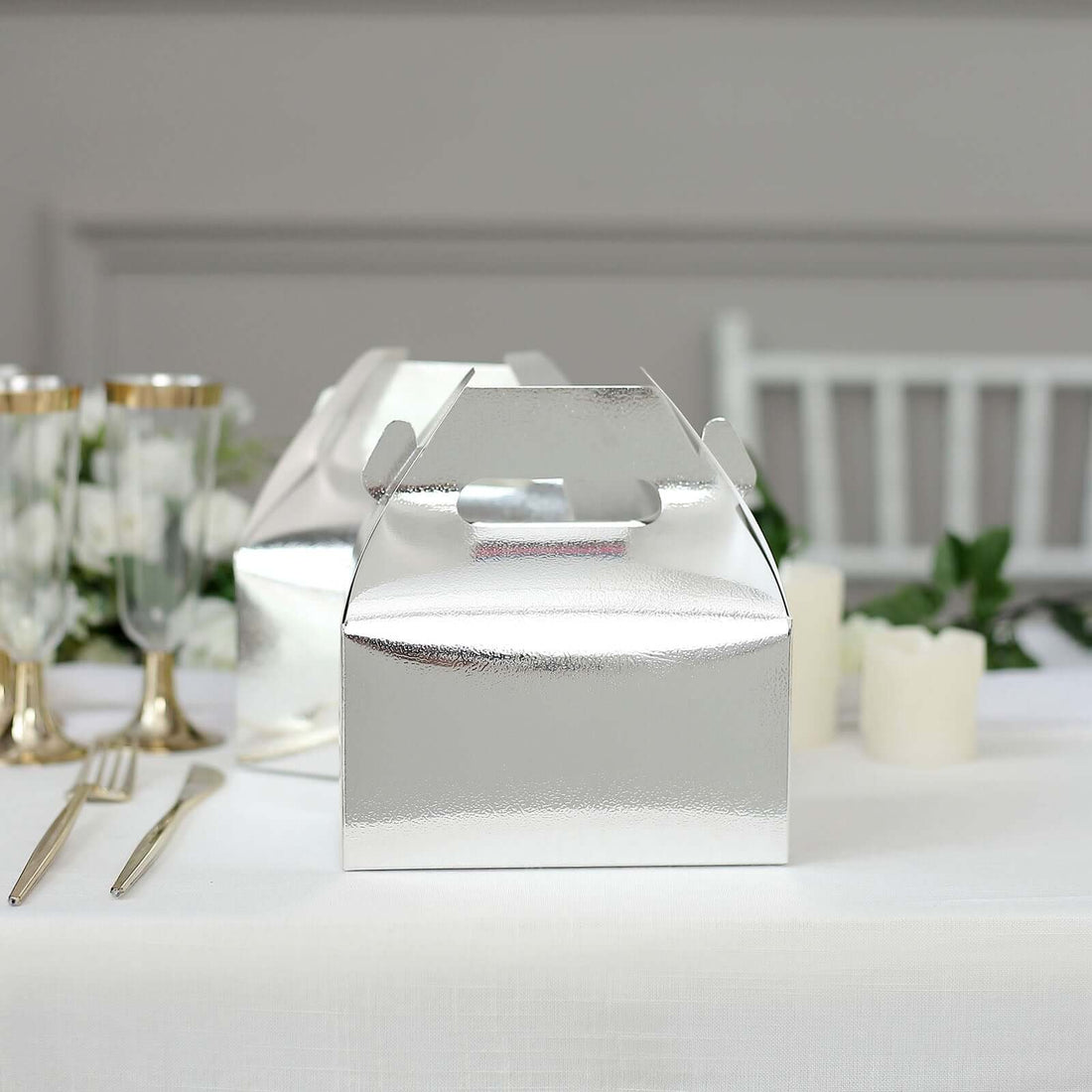 Shiny silver takeout box on a dining table with elegant decor.