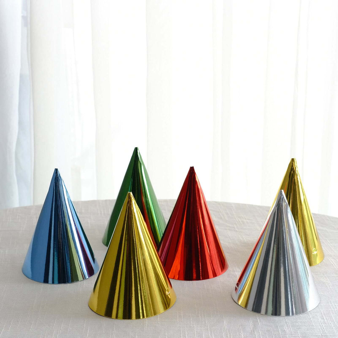 Colorful party hats in various metallic shades arranged on a table.