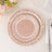 Decorative pink plate with floral design on a table setting.