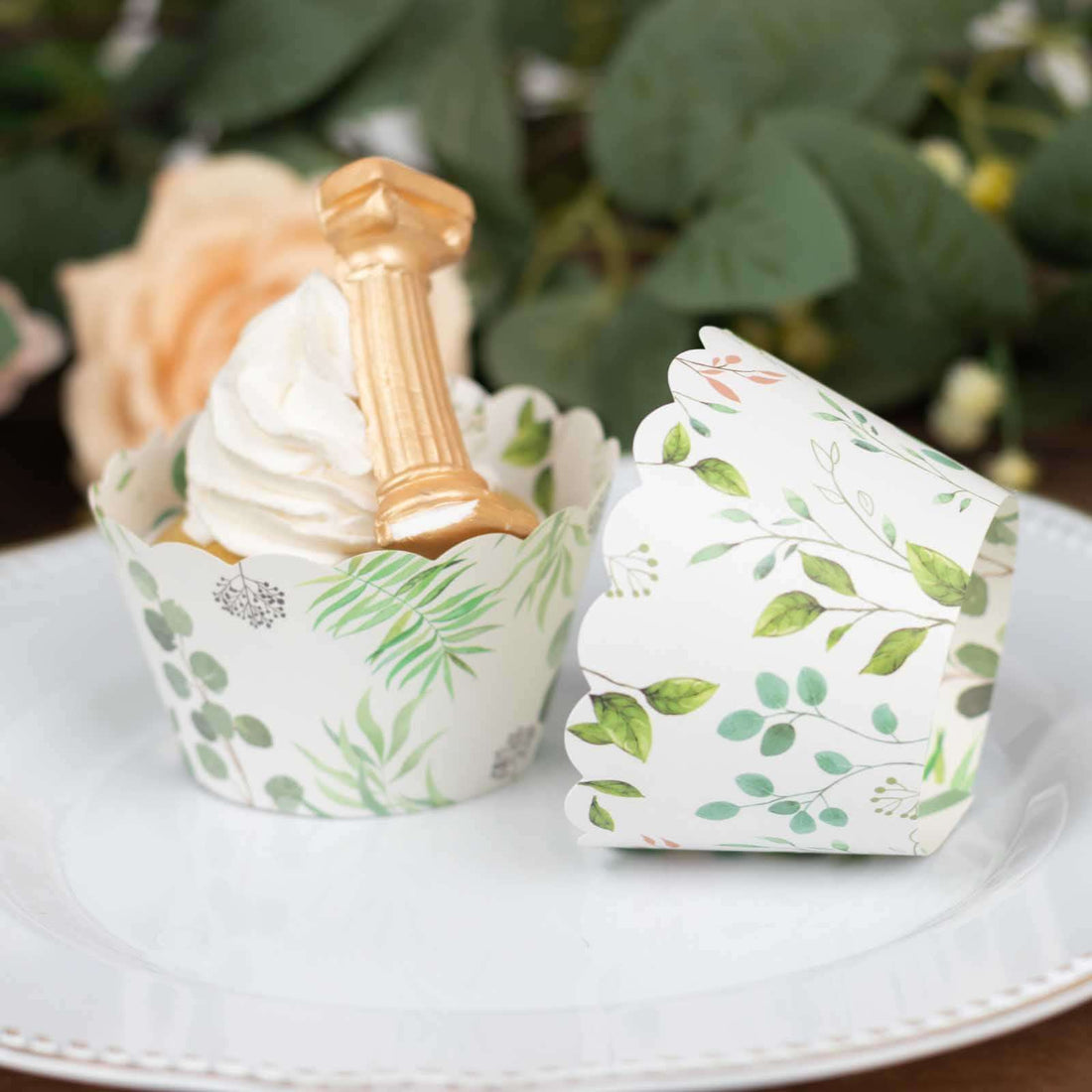 Floral cupcake wrappers with a golden decoration on a white plate.