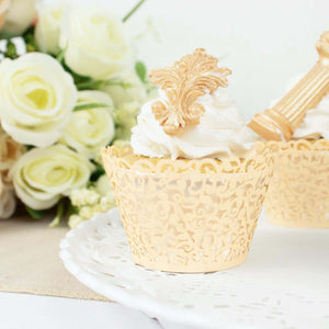 Decorative cupcake with golden topper and lace wrapper, surrounded by flowers.