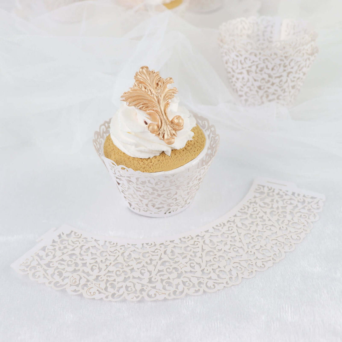 Elegant lace cupcake wrappers with gold accents and whipped cream topping.