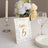 Table number card with floral design and gold accents on a dining table.