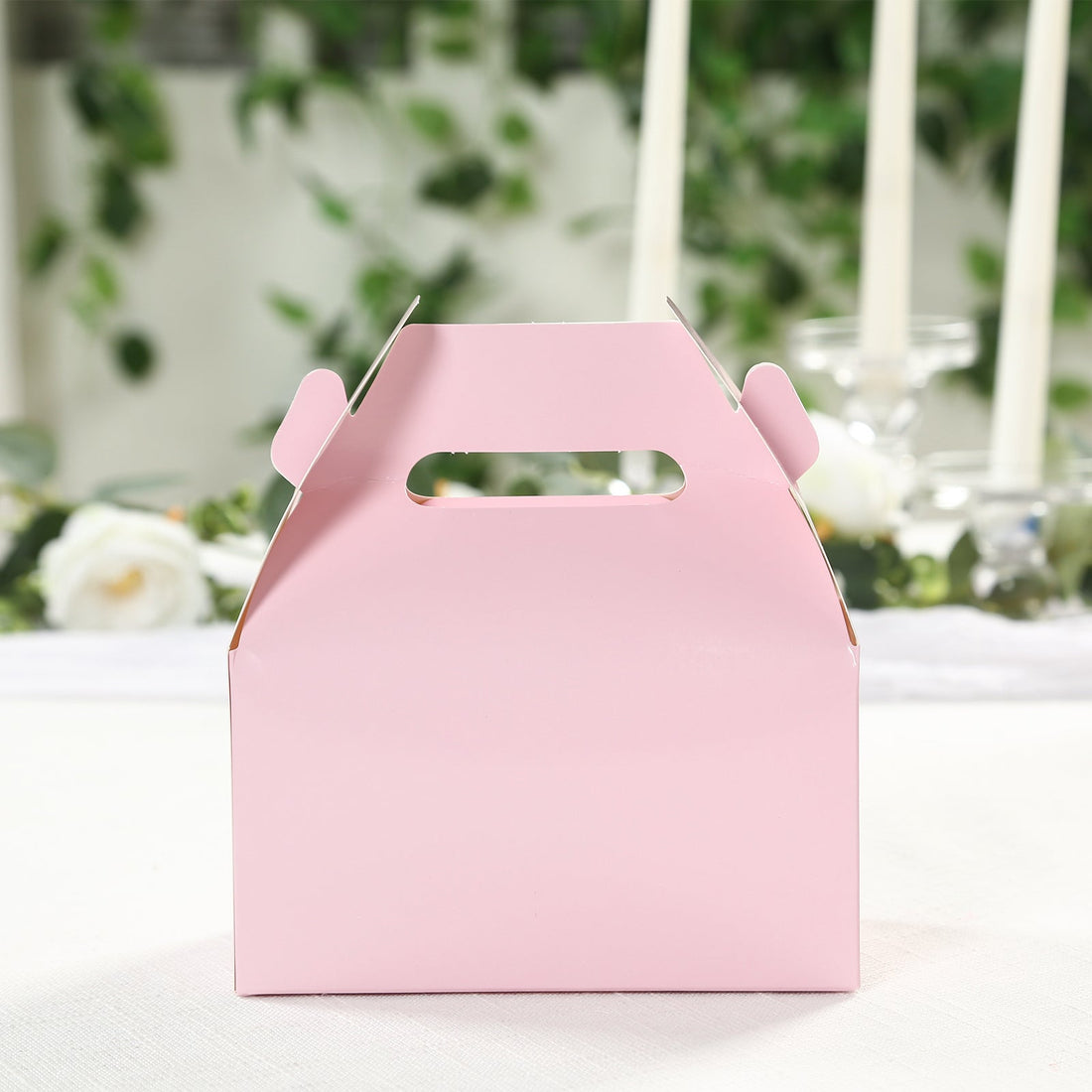 Pink gift box with handle on a plain background.