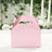 Pink gift box with handle on a plain background.