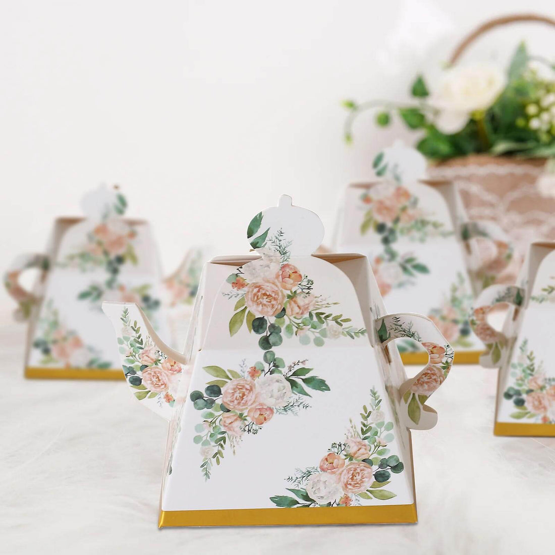 Decorative floral teapot with gold accents on a white backdrop.