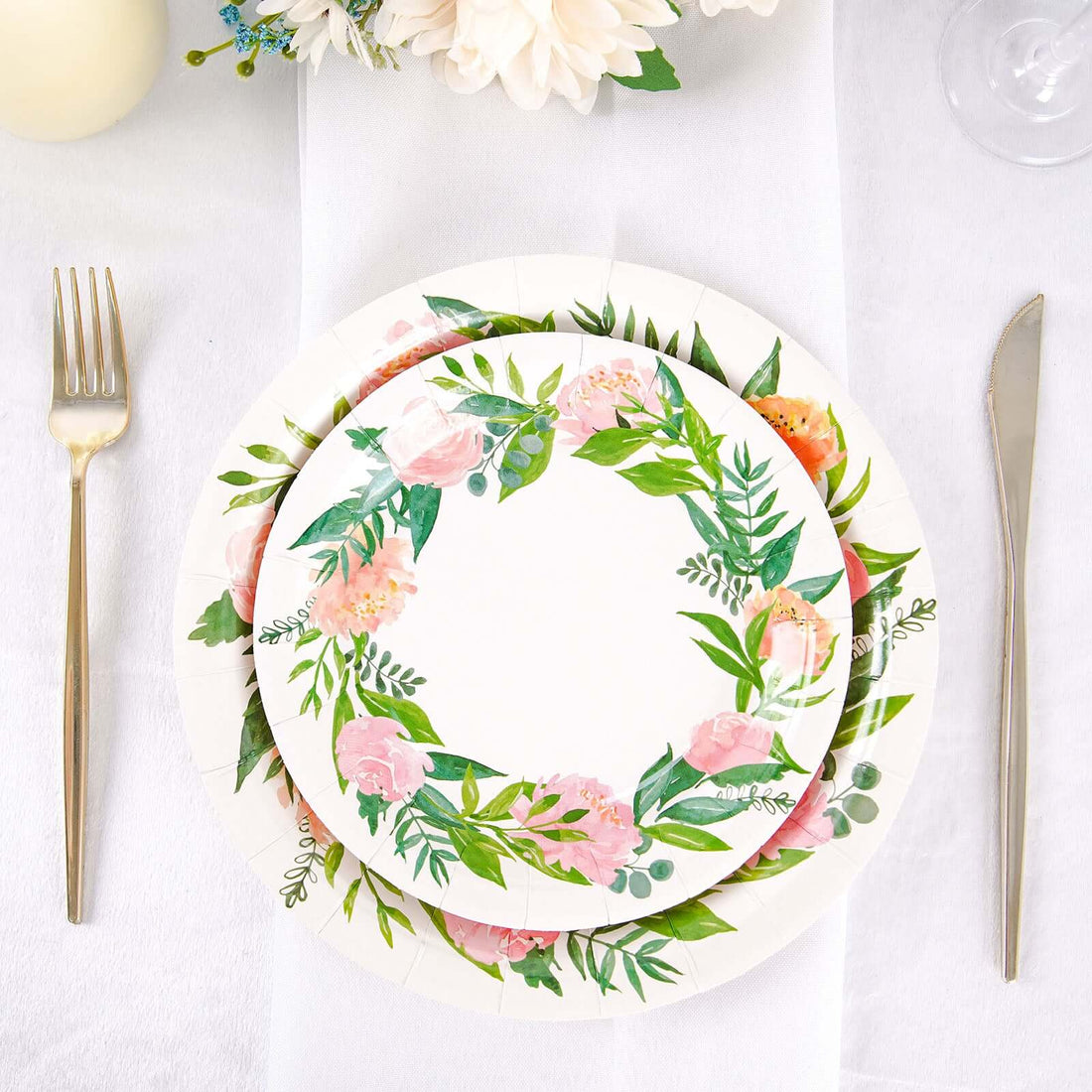 Floral paper plates stacked on a table with cutlery.