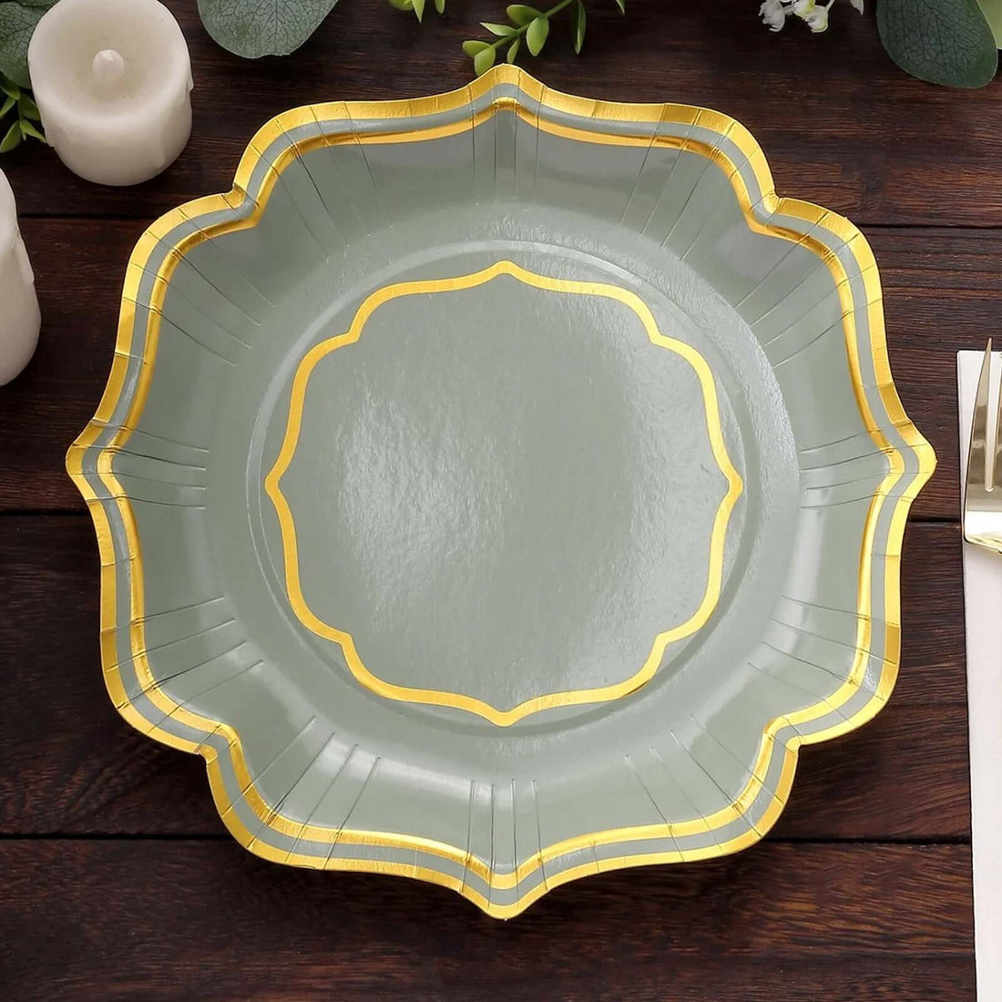 Elegant green paper plate with gold trim on a wooden table.