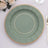 Green decorative plate with a gold rim on a table setting.