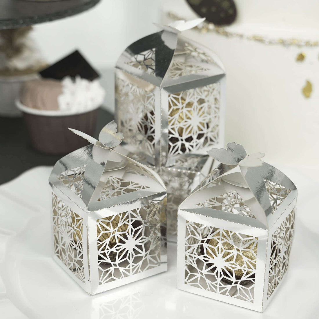 Decorative silver lanterns with intricate floral design and butterfly tops.