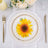 Sunflower decorative plate on a table setting with gold utensils.