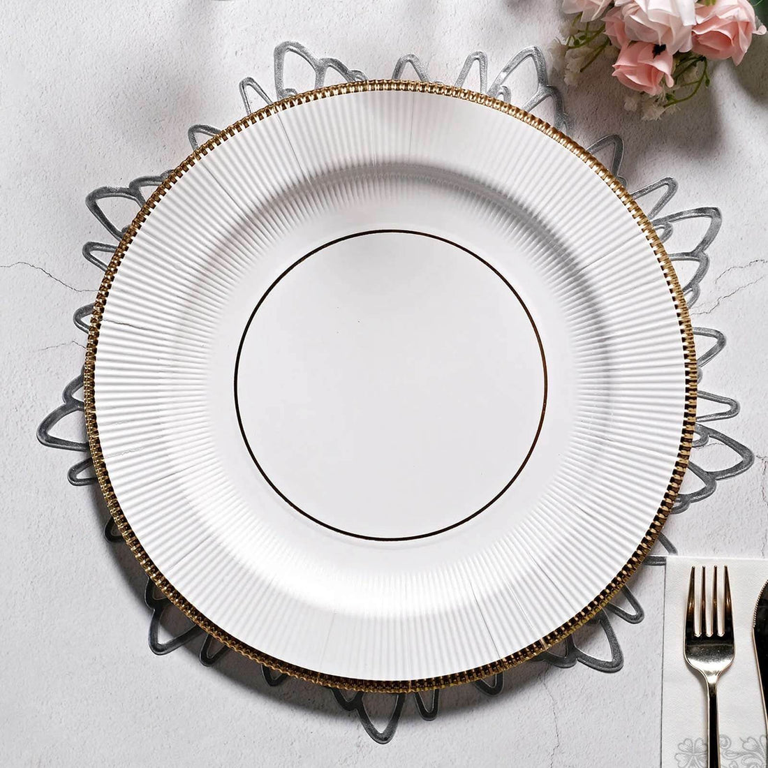 Elegant white plate with gold trim on decorative silver charger.
