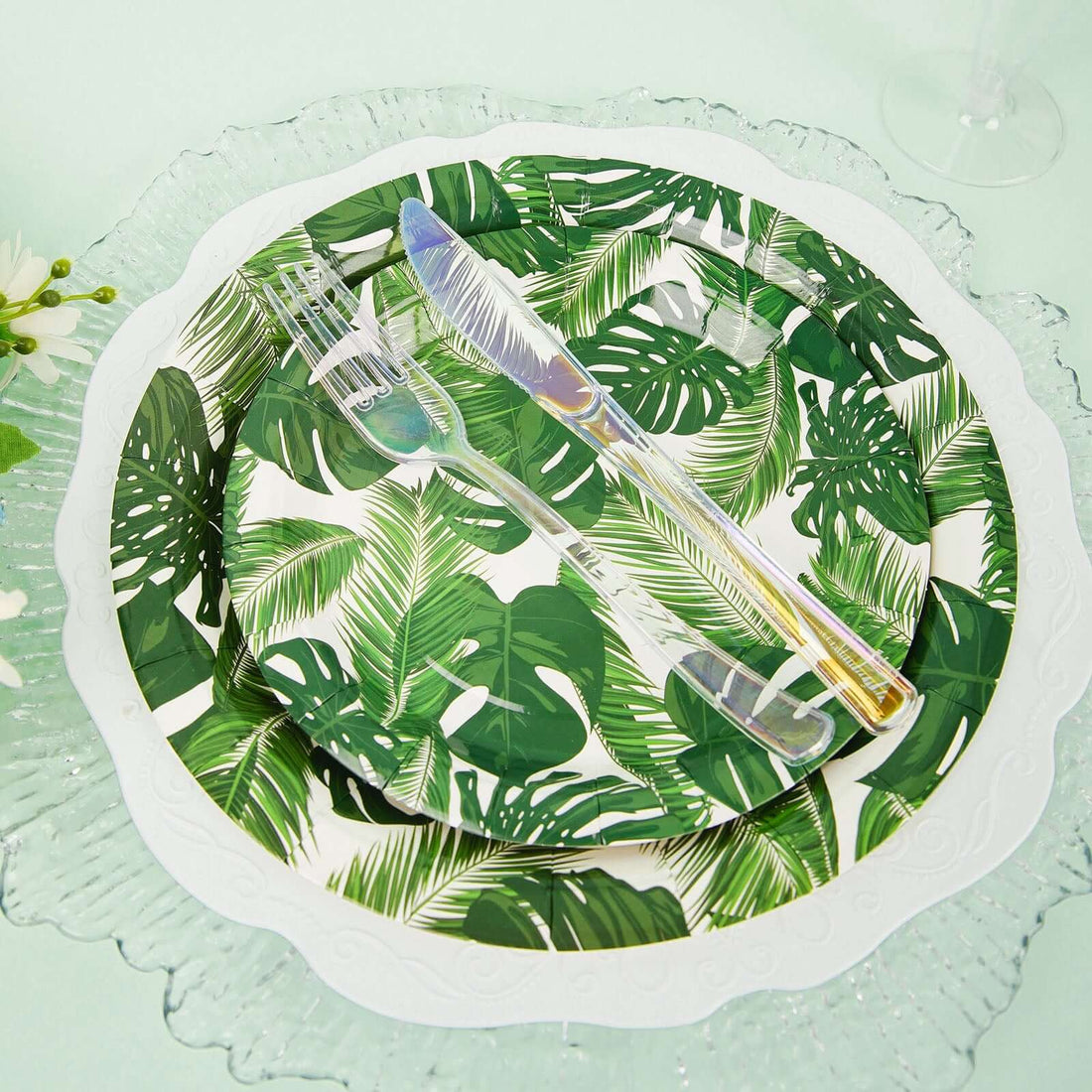 Tropical-themed dinnerware set with palm leaf designs and clear utensils.