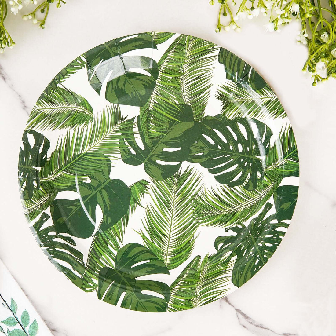 Green tropical leaf patterned plate on a marble surface.