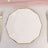 Elegant octagonal white plate with gold trim on textured surface.