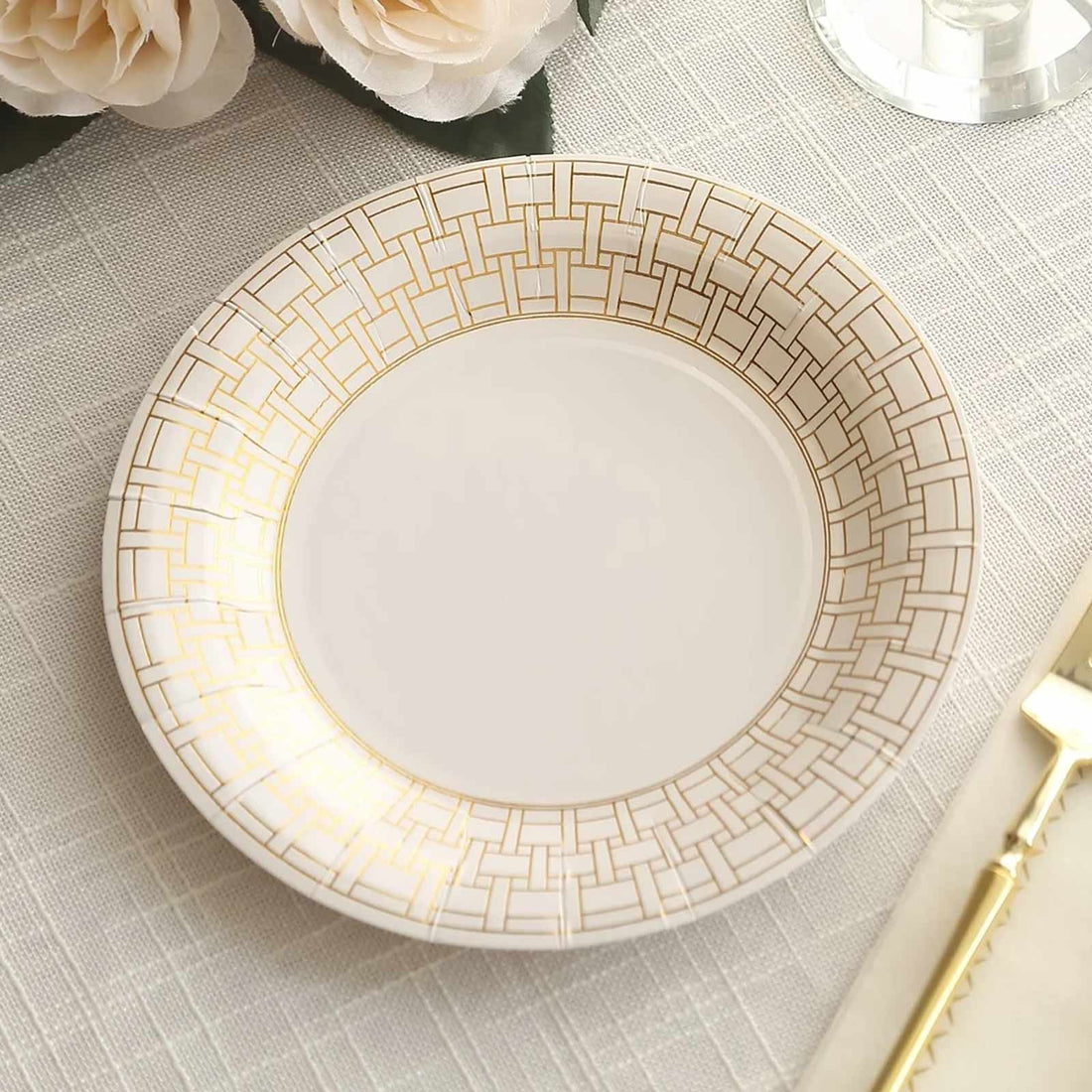 Elegant white plate with gold geometric pattern on a textured table setting.