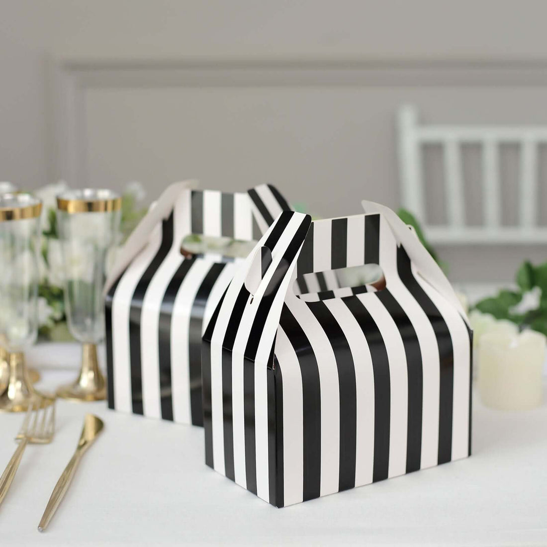 Black and white striped party favor boxes on a table setting.